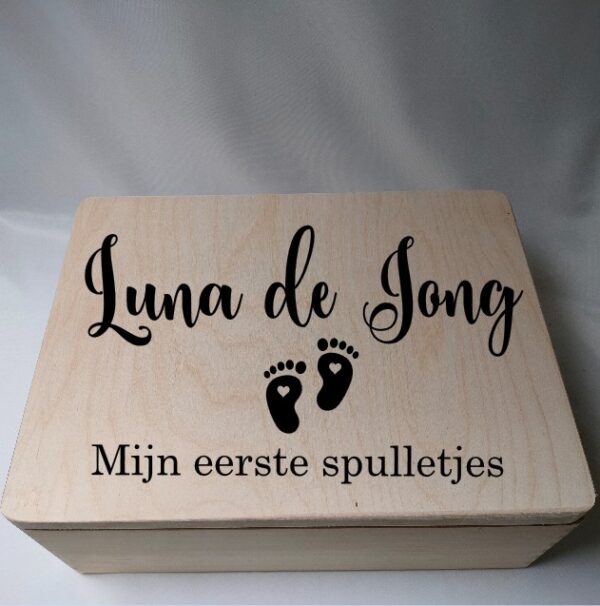 Houten bewaardoos met naam en voetjes en de tekst eerste spulletjes